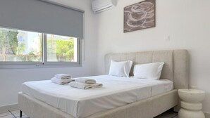 Une chambre à coucher comprenant un lit, une fenêtre, un appareil de climatisation et une œuvre d’art accrochée au mur.