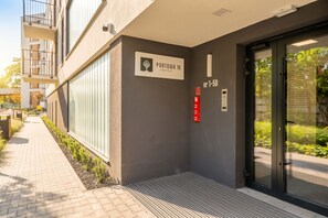 Entrada de un edificio con un cartel que indica 'PORTOWA 16' y un ascensor con el número de piso 'nr 1-50'.