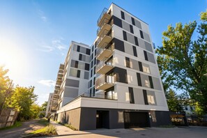Un immeuble résidentiel à plusieurs étages, doté de balcons, d’une entrée sécurisée et surplombant un ciel dégagé.