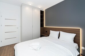 Un dormitorio moderno con una cama grande, un armario y estanterías empotradas.