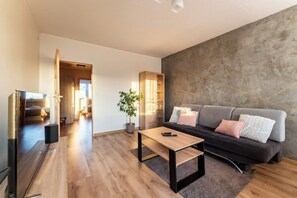 A modern living room with a sofa, a coffee table, and a television. - Gdańsk Burzyńskiego Cozy Stay Apartment (Gdańsk)