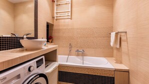 Een moderne badkamer met een ingebouwde wasmachine, een vrijstaand bad en een handdoekhouder.