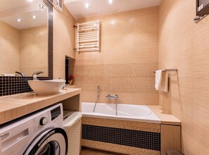 A modern bathroom with a built-in washing machine, a freestanding bathtub, and a towel rack. - Gdańsk Burzyńskiego Cozy Stay Apartment (Gdańsk)