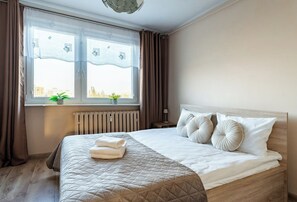 Ein Hotelzimmer mit Bett, einem Vorhangfenster, einem Heizkörper und Blick auf Gebäude.