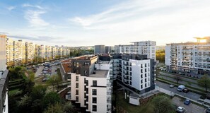 A high-rise residential building with multiple balconies, a parking lot, and a clear view of the surrounding urban landscape. - Gdańsk Burzyńskiego Cozy Stay Apartment (Gdańsk)