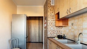 Eine kleine Küche mit Kühlschrank, Spüle und einem Stuhl.