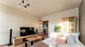 Een moderne slaapkamer met een bed, een televisie, een houten kast en een plant.