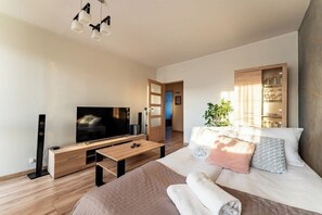 A modern bedroom with a bed, a TV, a wooden cabinet, and a plant. - Gdańsk Burzyńskiego Cozy Stay Apartment (Gdańsk)