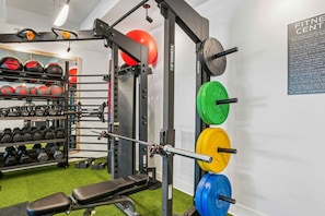 Un gimnasio con equipo de levantamiento de pesas, una banca y pelotas de ejercicio.