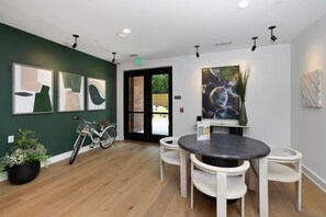 Un interior moderno con una mesa redonda y sillas, obras de arte en las paredes y una bicicleta en una esquina.