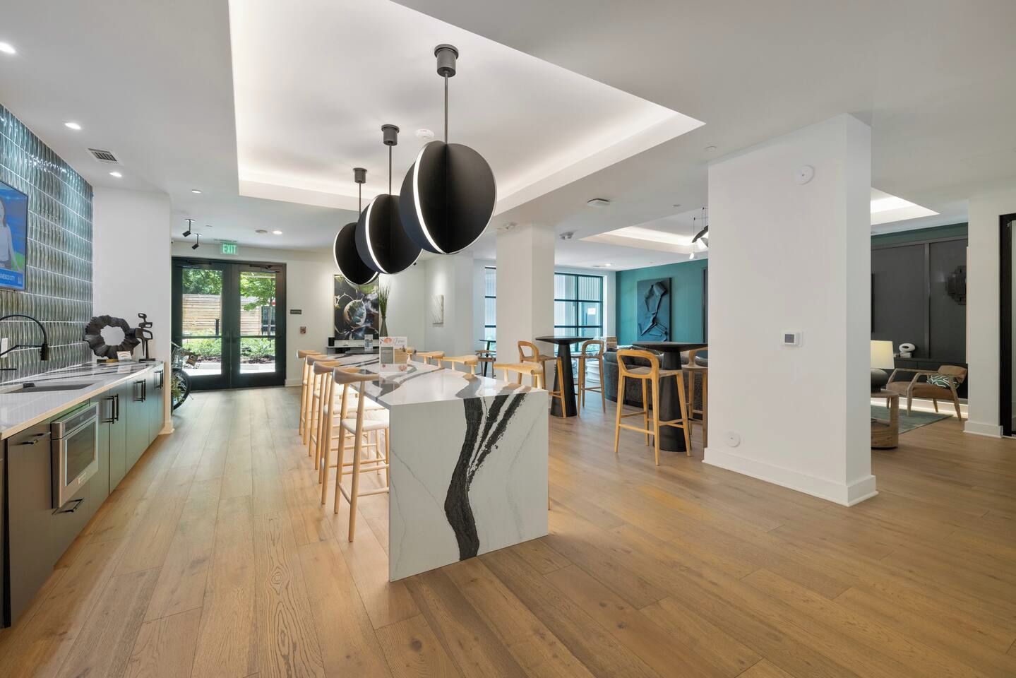 Una cocina moderna con una isla central, suelo de madera e iluminación colgante.