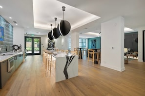 Una cocina moderna con una isla central, suelo de madera e iluminación colgante.
