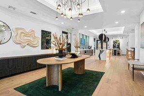 A modern interior with a round wooden table, a green rug, and a kitchen area in the background. - Walk to NoDa Arts District + Brew Pubs | King Bed (Charlotte)