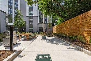 An outdoor patio area with a barbecue grill, seating, and a bike parking sign. - Walk to NoDa Arts District + Brew Pubs | King Bed (Charlotte)