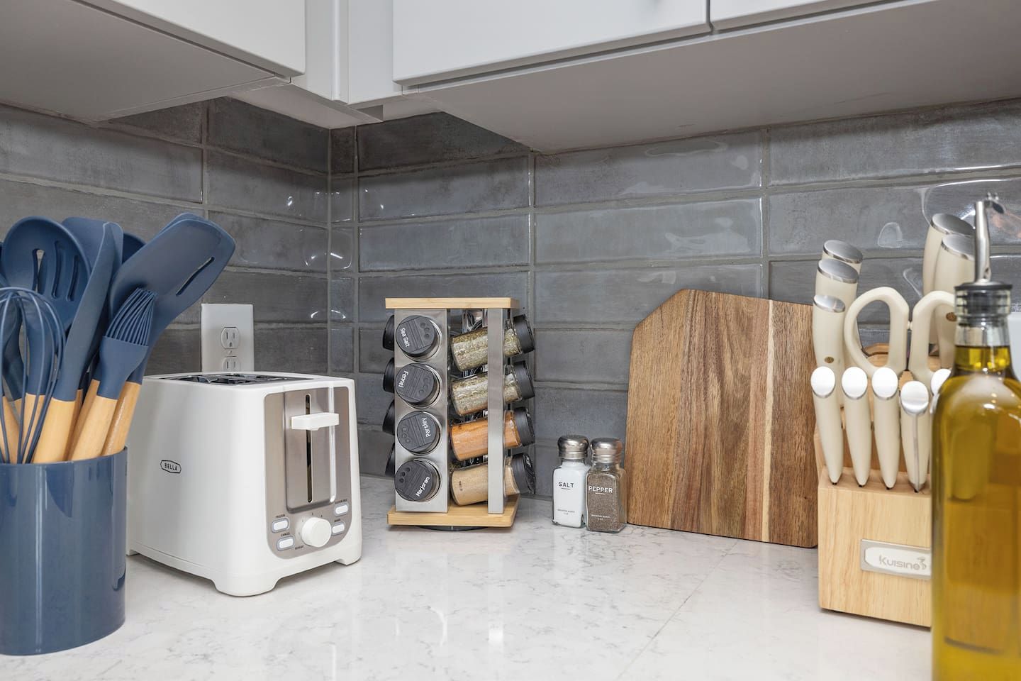 A kitchen with a white toaster, a spice rack, and a wooden cutting board.