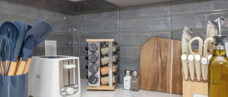 A kitchen with a white toaster, a spice rack, and a wooden cutting board.