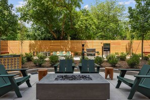 An outdoor seating area with a fire pit, green chairs, and a wooden fence. - Walk to NoDa Arts District + Brew Pubs | King Bed (Charlotte)