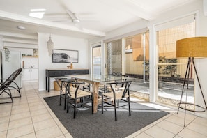 A modern kitchen with a dining area, a chandelier, and a view of the outdoors. - The Palms - private yard & parking, 200m to beach (Margate)