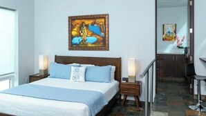 A bedroom with a bed, bedside lamps, a ceiling fan, a painting on the wall, and a view of a bathroom through an open door. - NEW! Dreamy & Spacious 5-bedroom house with generator in Cruz Bay with Pool (Cruz Bay)