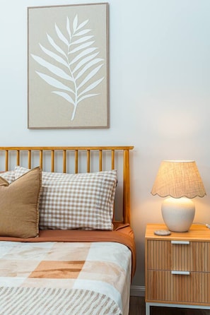 A bedroom with a bed, a nightstand, a lamp, and a wall-mounted artwork.