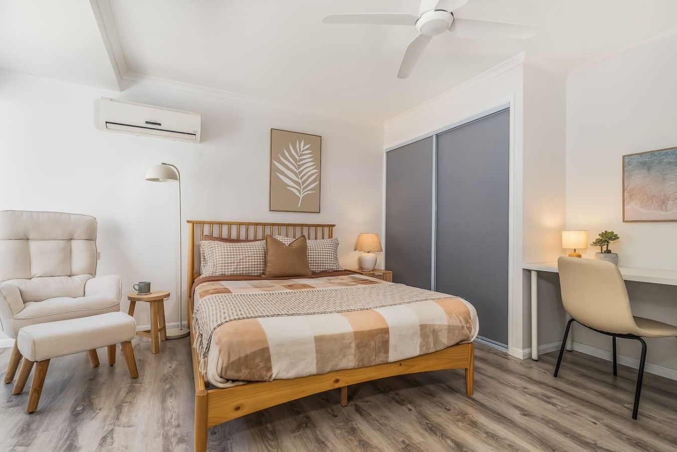 Ein Schlafzimmer mit einem Bett, einem Sessel, einem Schreibtisch und einem Deckenventilator.
