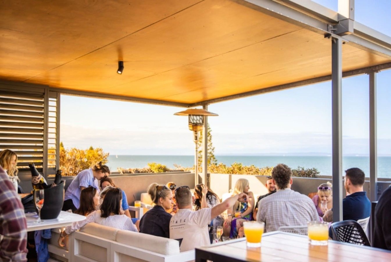 An outdoor dining area with tables and chairs, overlooking a body of water.