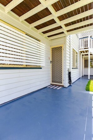 A covered porch with a blue floor, white siding, and a wooden ceiling.