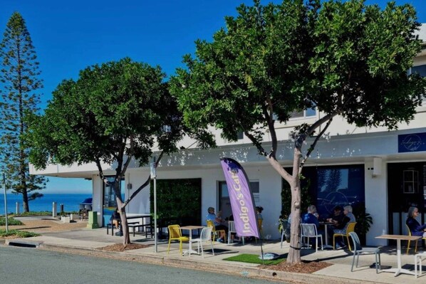 An outdoor seating area with tables and chairs, a flag, and a view of the ocean.
