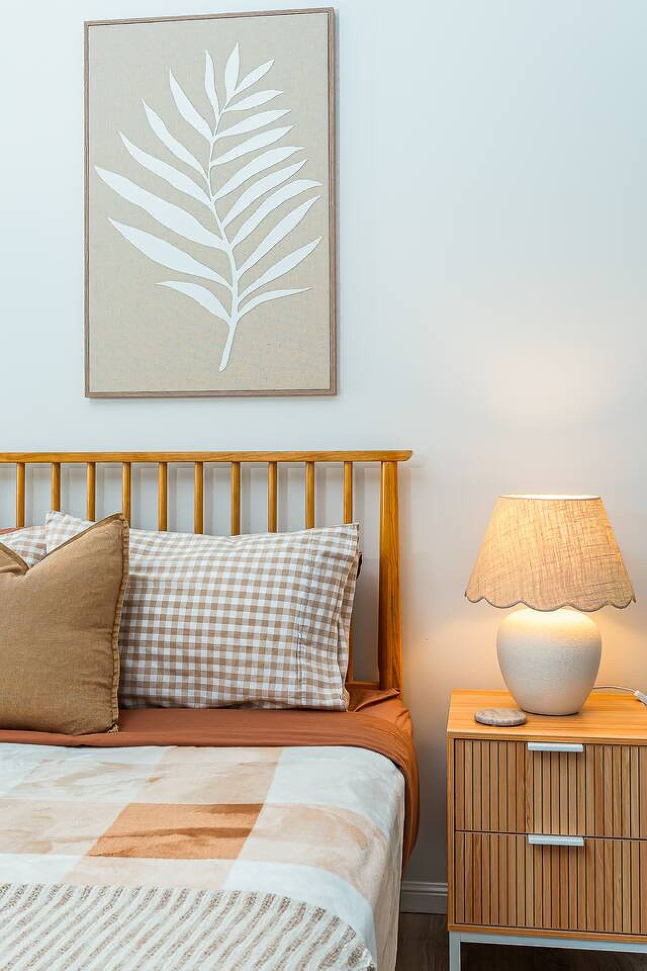 A bedroom with a bed, a nightstand, a lamp, and a wall-mounted artwork.