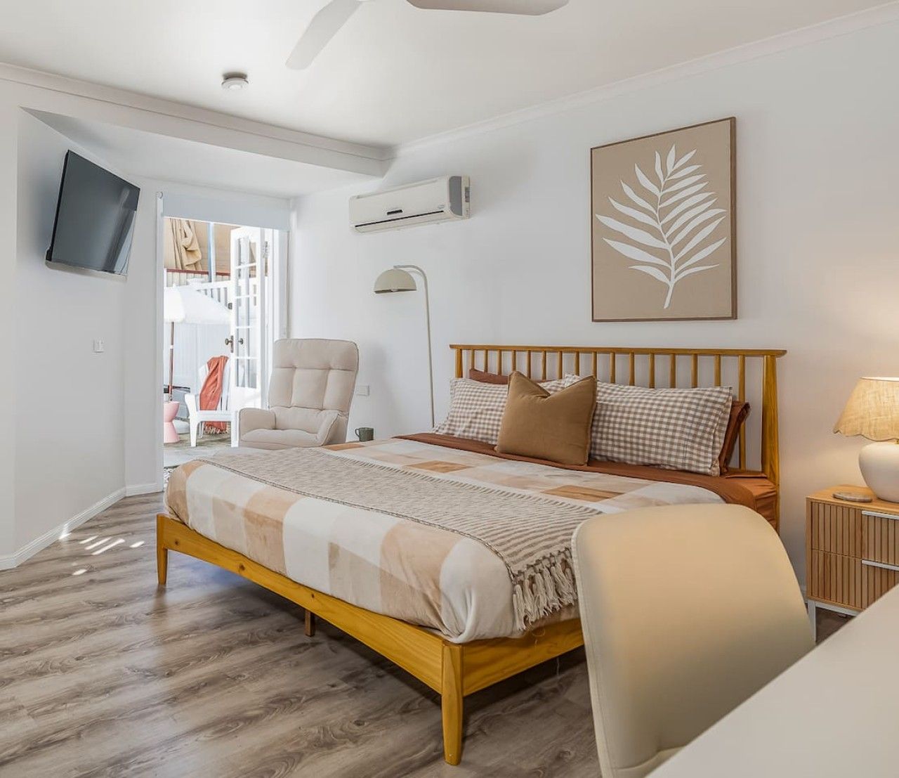 Un dormitorio con cama, una silla, televisor y aire acondicionado de pared.
