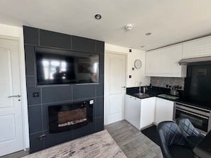 A modern kitchen with a built-in TV, a fireplace, and a stainless steel oven.
