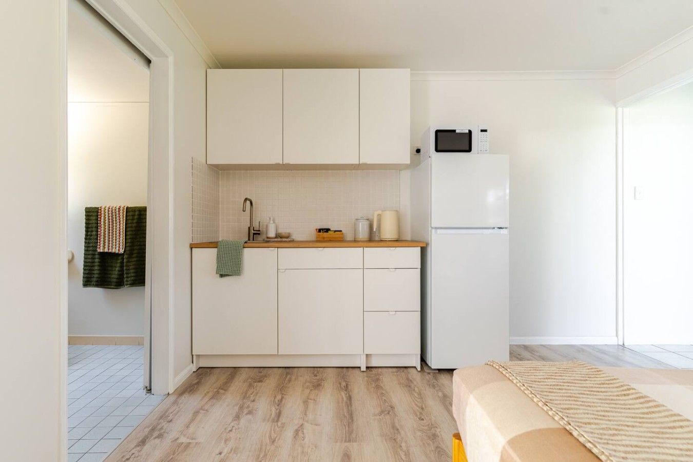 A compact kitchen with white cabinets, a microwave, and a refrigerator.