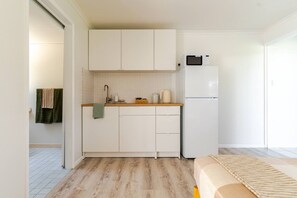 A compact kitchen with white cabinets, a microwave, and a refrigerator.