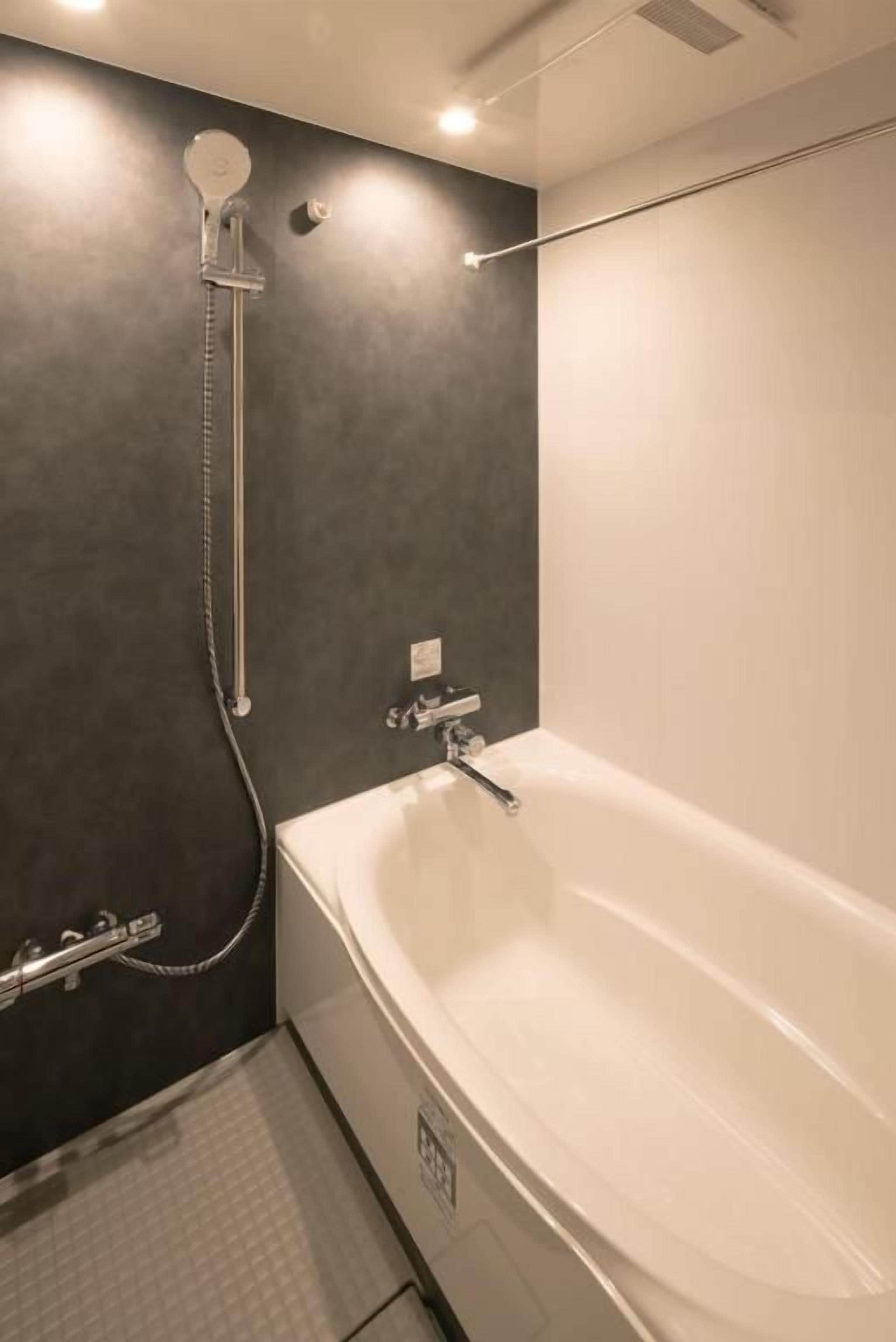 A modern bathroom with a bathtub, shower, and a dark wall.