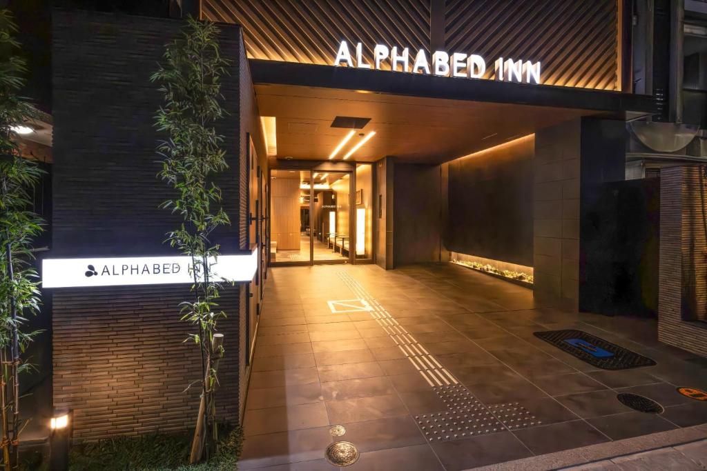 The entrance to the Alphabed Inn with a modern design, including a sign above the door and a pathway leading inside.