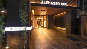 The entrance to the Alphabed Inn with a modern design, including a sign above the door and a pathway leading inside.