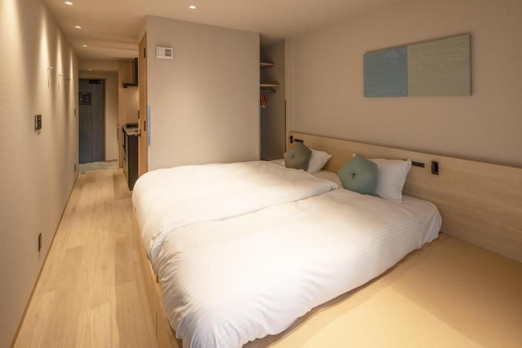 A hotel room with a large bed, a wardrobe, and a painting on the wall.