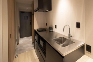 A compact kitchen with a stainless steel sink, a coffee maker, and a built-in oven. - ALPHABED INN Hakata station front (fukuokashi hakataku hakataekimae)