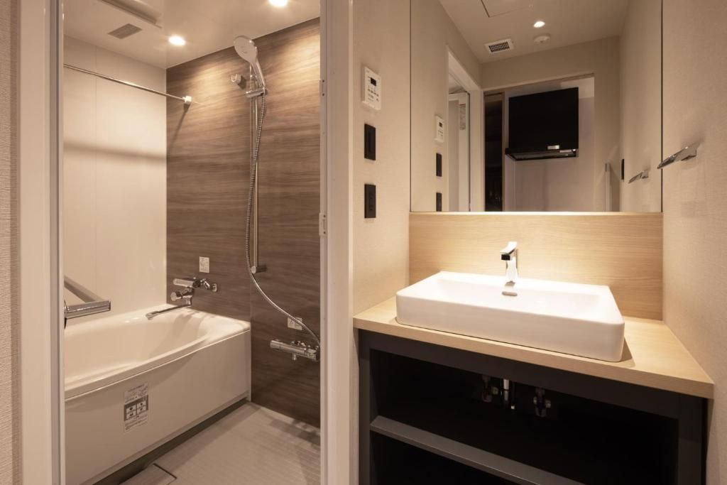 A modern bathroom with a bathtub, a shower, and a vanity with a sink.