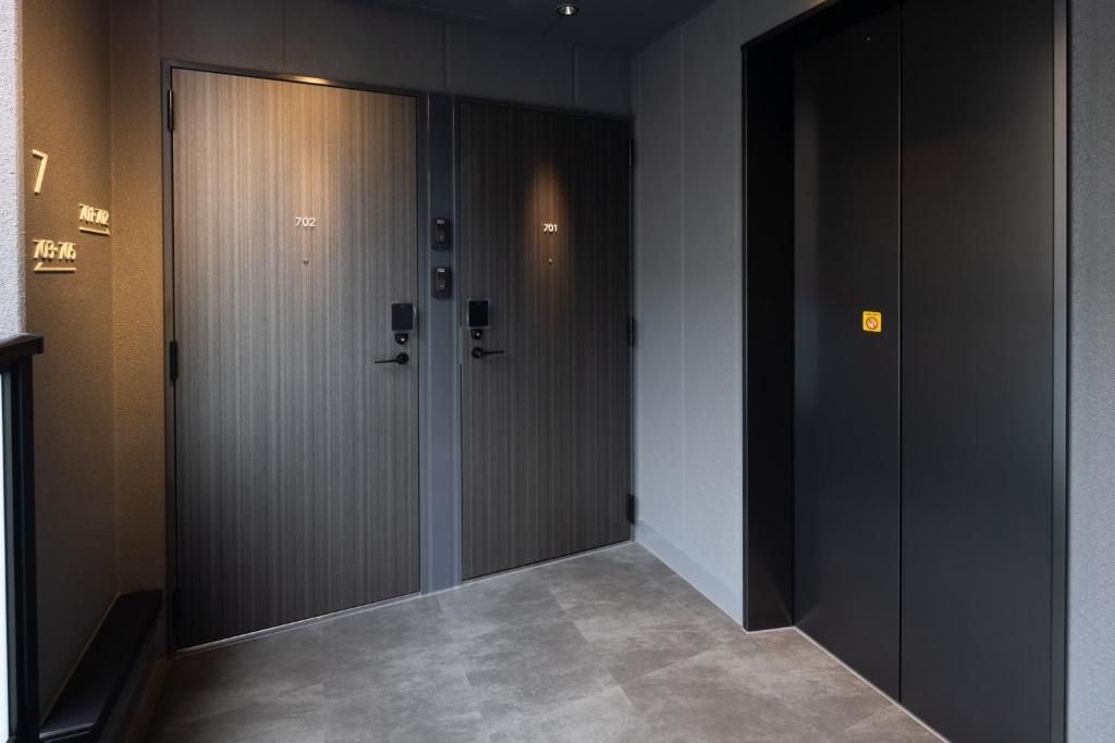 A hallway with two doors, one labeled 702 and another with a yellow sign, leading to a room.
