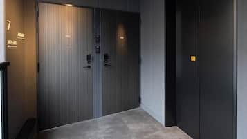 A hallway with two doors, one labeled 702 and another with a yellow sign, leading to a room.