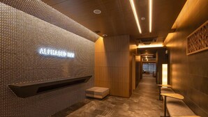 Un interior modern amb una paret amb textura, una banca i una zona de seients.