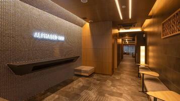 A modern interior with a textured wall, a reception desk, and seating areas.