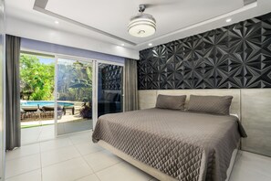 Ein modernes Schlafzimmer mit einem großen Bett, einer Wand mit geometrischem Muster und Blick auf einen Pool durch eine Schiebetür.