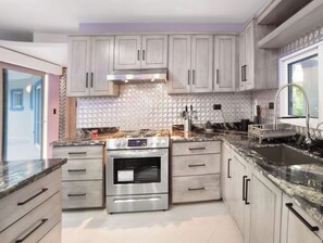 A modern kitchen with stainless steel appliances, light-colored cabinets, and a patterned backsplash. - Marvelous 4-bedroom house with AC in peaceful Sosúa neighborhood (Sosúa)