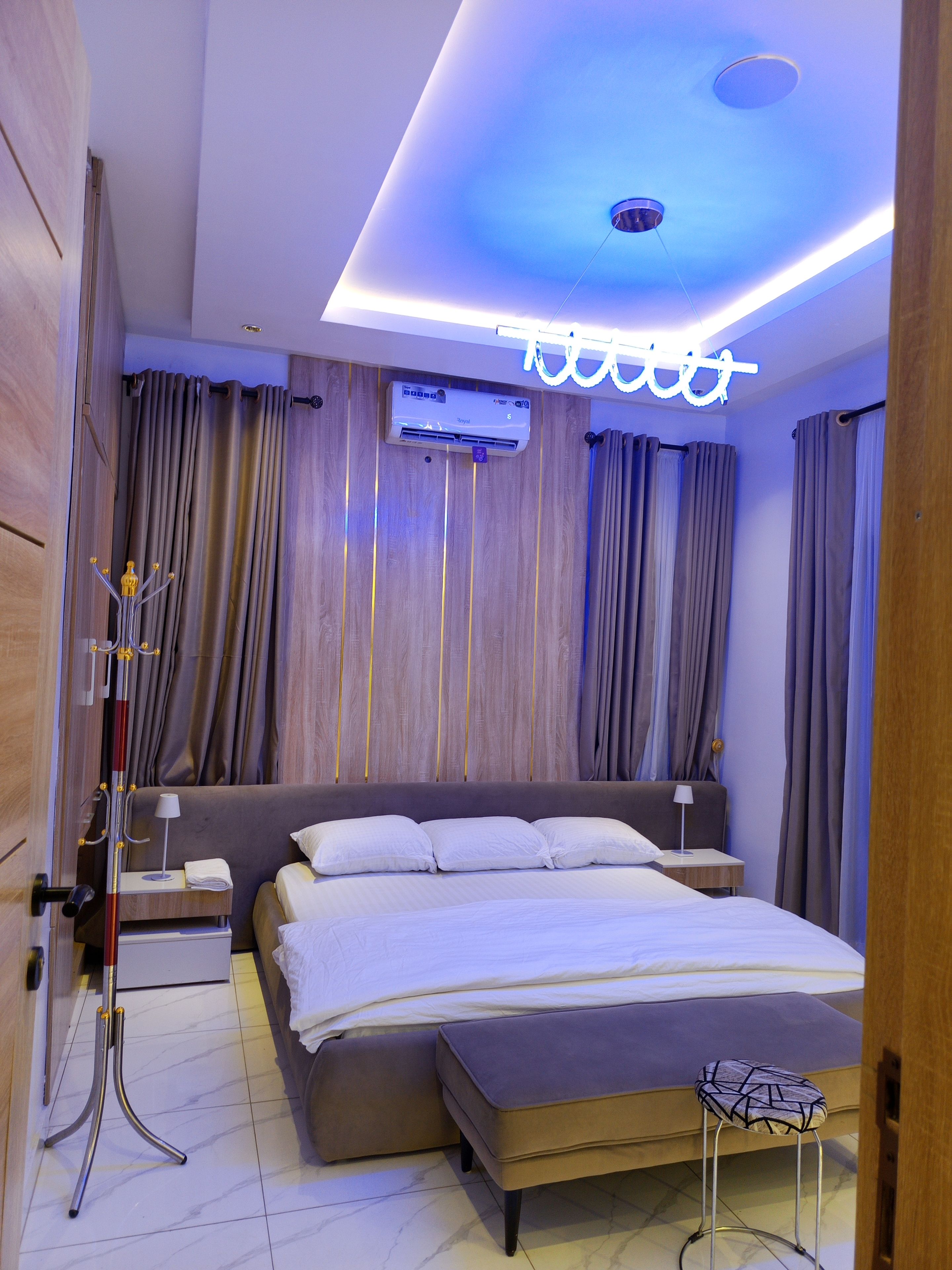 Una habitación de hotel moderna con una cama grande, mesitas de noche, un escritorio e iluminación en el techo.