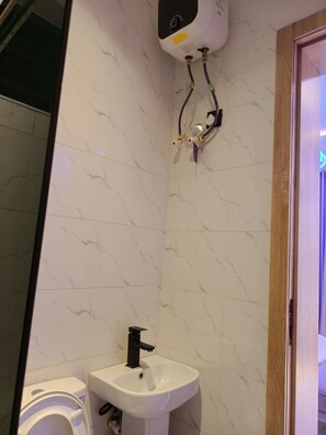 A bathroom with a toilet, sink, and a water heater mounted on the wall. - Your Home Away From Home – Comfort, Peace & Warm Hospitality (Lagos)