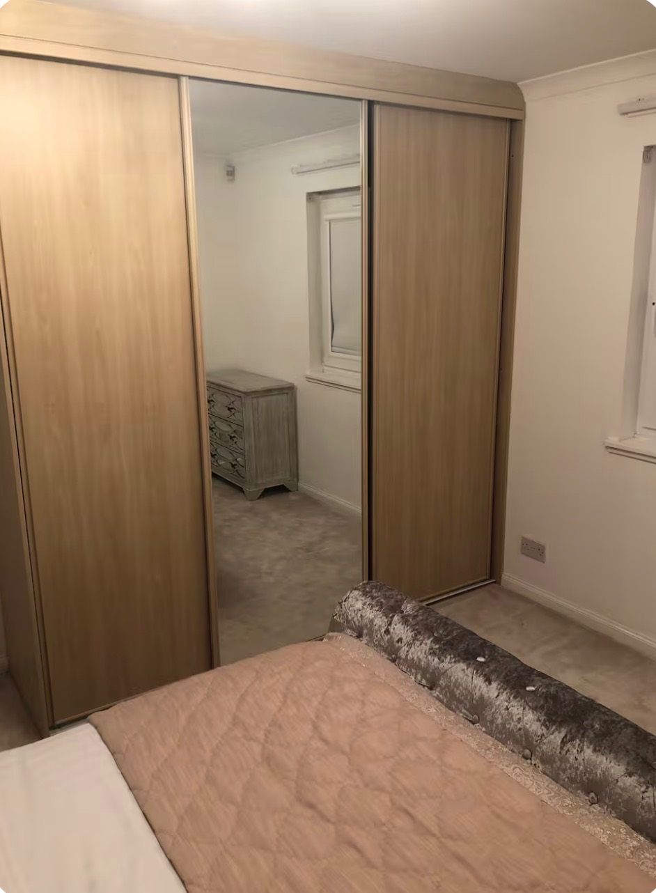 A bedroom with a bed, a wardrobe, and a dresser.