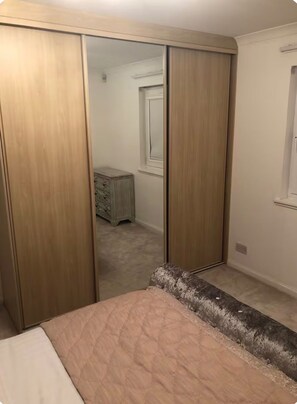 A bedroom with a bed, a wardrobe, and a dresser.