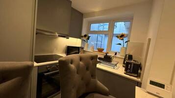 A compact kitchen with a built-in oven, a microwave, and a coffee maker. There is a window with a view of the outside.